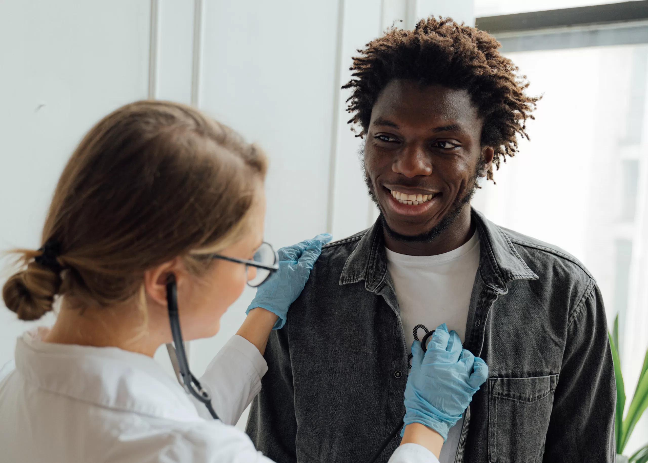 Young male has female medical care provider listen to heart via stethoscope